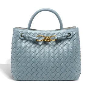 Detailed view of light blue woven leather handbag featuring elegant gold tone knot hardware design.