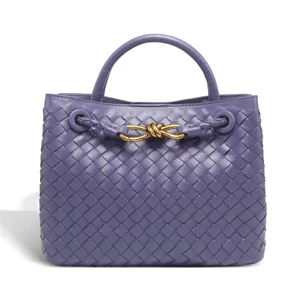Purple woven leather handbag with gold metal knot detail, elegant luxury tote bag close-up.