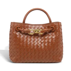 Close-up of brown woven leather handbag detail featuring metal knot hardware and sturdy handles.