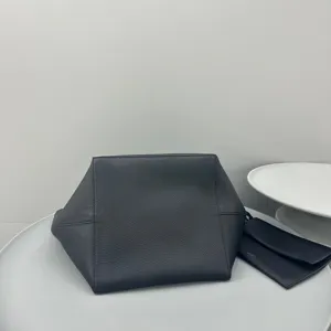 Detailed view of minimalist black leather tote bag with matching small pouch, elegant daily bag.