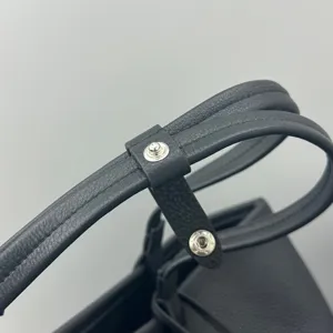 Detailed view of black leather tote bag handle, premium cowhide material with metal snap closure.