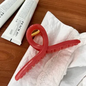 Detailaufnahme einer roten Gelee-Haarklammer in Kleiderbügelform auf Holztisch.