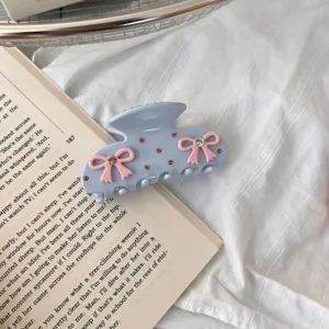 Rhinestone bow acetate hair claw detail, sweet hair clip accessory for elegant styling.