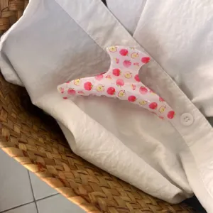 Gros plan détail de la jolie pince à cheveux rose clair motif pomme, accessoire.