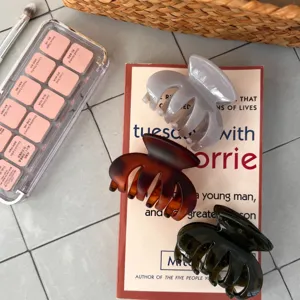 Detailansicht von drei kleinen Haarklammern aus Kunststoff in verschiedenen Farben auf einem Buch.