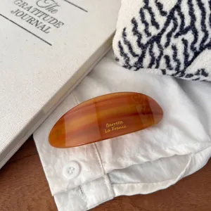 Detailed view of the large resin hair clip featuring a dazzling amber texture and gold text.