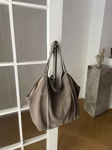 Grey suede tote bag detail, slouchy luxury design with slender straps and ample capacity.