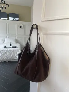 Detailed shot of a dark brown suede tote bag, large capacity, casual slouchy shoulder style.