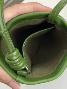 Dettaglio borsa telefono in pelle verde, pelle conciata al vegetale, design con nodo raffinato.