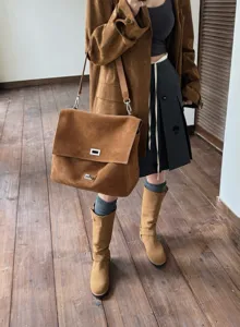 Detailed view of the autumn winter brown suede leather shoulder bag with flap and metal lock.