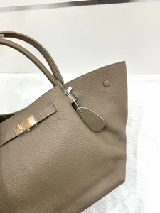 Classic taupe leather winged tote bag for women, stylish top handle handbag with metal closure.