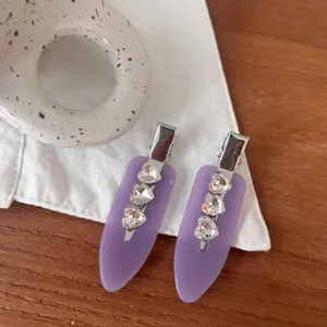 Close-up detail of purple matte hair clips decorated with shiny crystal heart rhinestones.