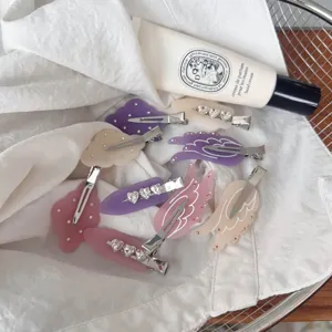 Close-up of aesthetic matte acrylic hair clips with angel wings and cute cloud designs in pastel tones.
