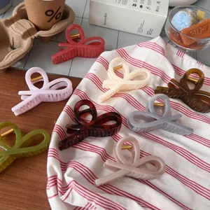 Detailed view of colorful ribbon hair claw clips displayed on striped fabric, lifestyle style.