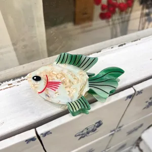 Primo piano dettagliato di un fermaglio per capelli in acetato a forma di pesce marino.