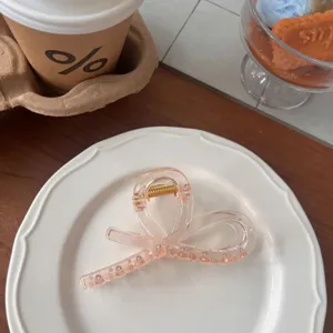 Elegant translucent pink ribbon bow hair claw clip, detailed view of cute hair accessory.