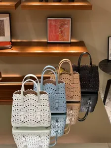 Detailed view of multiple colored leather laser-cut tote bags displayed on reflective table.