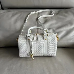 White woven leather boston bag detail, top handles and shoulder strap, elegant style.