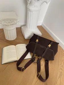 Detail shot of dark brown suede vintage backpack with shoulder straps and golden metal hardware.