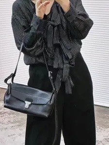 Detailed view of black genuine leather messenger shoulder bag, vintage style closeup.