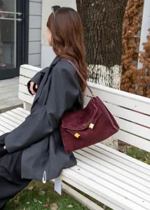 Burgundy suede shoulder bag detailed view, showing premium leather texture and metal hardware.