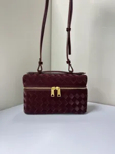 Detailed shot of the glossy woven vanity bag, showing fine texture and gold zipper.