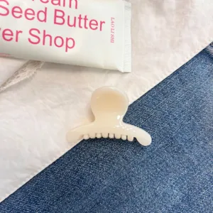 Nahaufnahme einer milchigen Jelly-Haarklammer mit rundem Design auf Jeansstoff-Hintergrund.
