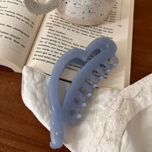 Detalle de pinza de pelo de corazón azul, accesorio minimalista de resina para uso diario.