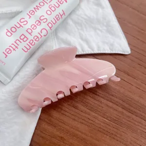 Primo piano ravvicinato sui dettagli del fermacapelli rosa in acetato con superficie lucida.
