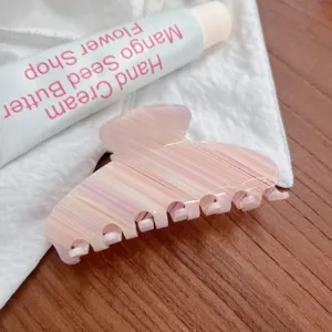 Dettaglio molletta per capelli in acetato rosa con texture marmorizzata e design elegante.