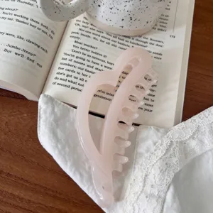 Vista detallada de pinza de pelo rosa en resina sobre libro abierto y encaje, estilo aesthetic.