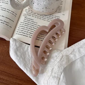Primer plano detallado de la elegante pinza de pelo de corazón en rosa suave, ideal para diario.
