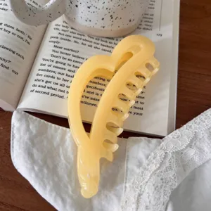 Primer plano detalle de una linda pinza para el pelo acrílica amarilla en forma de corazón.