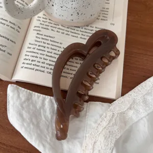 Primer plano de una pinza para el pelo en forma de corazón marrón en un libro, detalle estético.