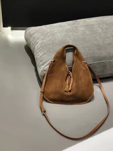 Detail shot of a brown suede triangular hobo bag featuring soft texture and stylish strap.