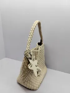 Woven leather bucket bag for women, stylish braided shoulder tote with star charm.