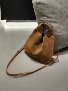 Brown suede triangle shoulder bag detail, premium frosted leather texture with metal hardware.