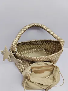 Close-up detail of the gold woven tote bag interior, showing structured lining and cute star charm.