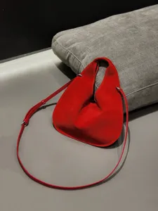 Red suede leather triangular shoulder bag, stylish dumpling crossbody handbag with sleek strap.