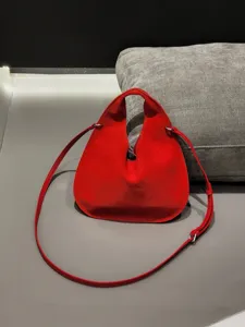 Red suede triangular handbag detail showing the soft leather texture and cutout handle design.