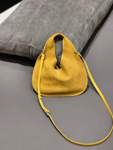 Yellow suede triangular hobo crossbody bag detail showcasing smooth texture and fine strap.