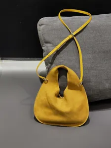 Yellow suede dumpling bag detail showing smooth texture, adjustable strap and hardware.
