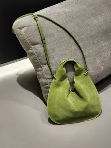Green suede triangle bag detail view, soft leather dumpling crossbody handbag for women.