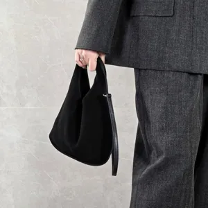 Black suede triangle bag detail showing premium genuine leather texture and strap design.
