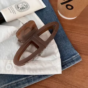 Dettaglio in primo piano della molletta per capelli marrone cava, elegante accessorio moda.