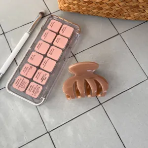 Detailansicht einer schicken karamellbraunen Haarklammer auf einer modernen grauen Fliese.
