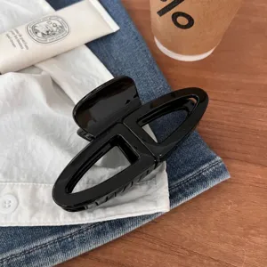 Molla per capelli geometrica nera in dettaglio, elegante design francese per acconciatura.
