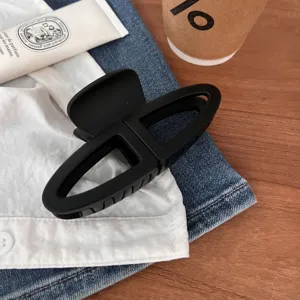 Dettaglio molletta per capelli geometrica nera, design minimalista per acconciature eleganti.