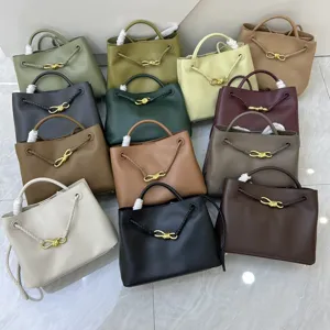 Detailed view of stylish plain leather handbags with braided handles and golden knot hardware.