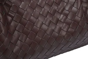 Close-up of premium brown woven leather handbag detail showing fine craftsmanship and texture.